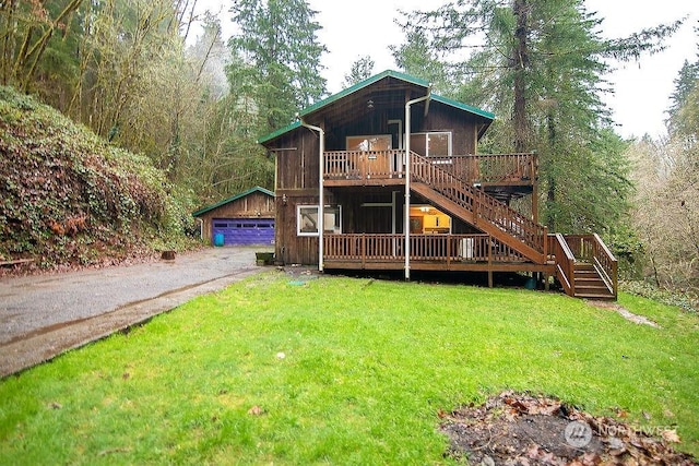 exterior space featuring a yard, a wooden deck, an outbuilding, and a garage