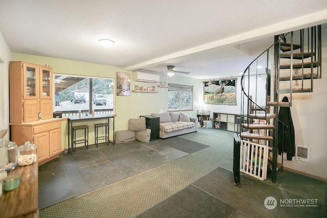 carpeted living room with a wall unit AC, ceiling fan, and a textured ceiling