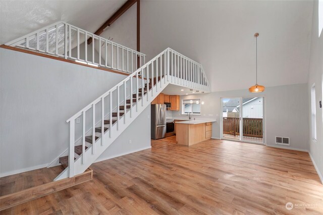 unfurnished living room with light wood-type flooring, high vaulted ceiling, and sink