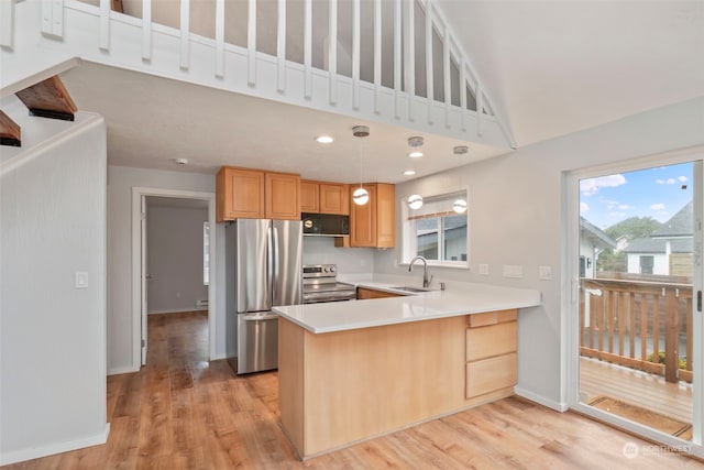 kitchen with sink, hanging light fixtures, light hardwood / wood-style floors, kitchen peninsula, and stainless steel appliances