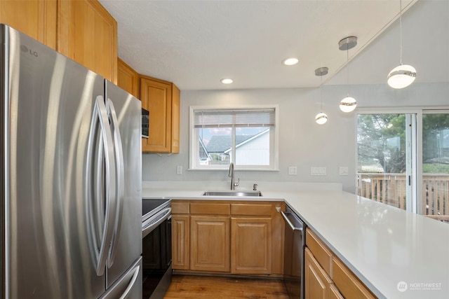 kitchen with pendant lighting, hardwood / wood-style floors, sink, kitchen peninsula, and stainless steel appliances