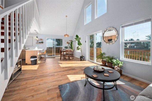 585 Ocean Shores Blvd SW, Ocean Shores, WA 98569 - living room featuring a towering ceiling, stairway, light wood-style floors, and baseboards