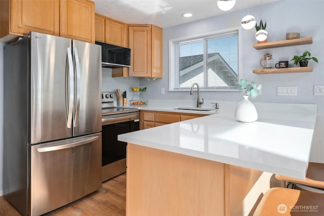 585 Ocean Shores Blvd SW, Ocean Shores, WA 98569 - kitchen featuring appliances with stainless steel finishes, a sink, light countertops, light wood-style floors, and a peninsula