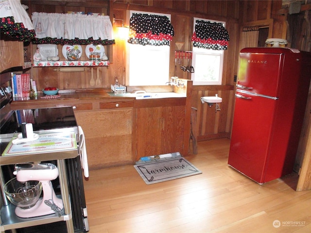 kitchen with wood walls, refrigerator, and light wood-type flooring