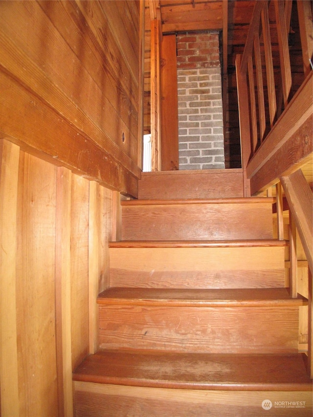 stairway featuring wood walls