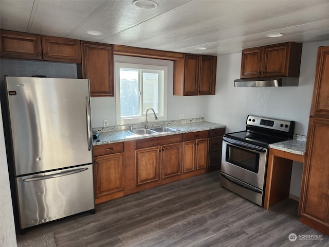 kitchen with light stone countertops, appliances with stainless steel finishes, dark hardwood / wood-style flooring, and sink