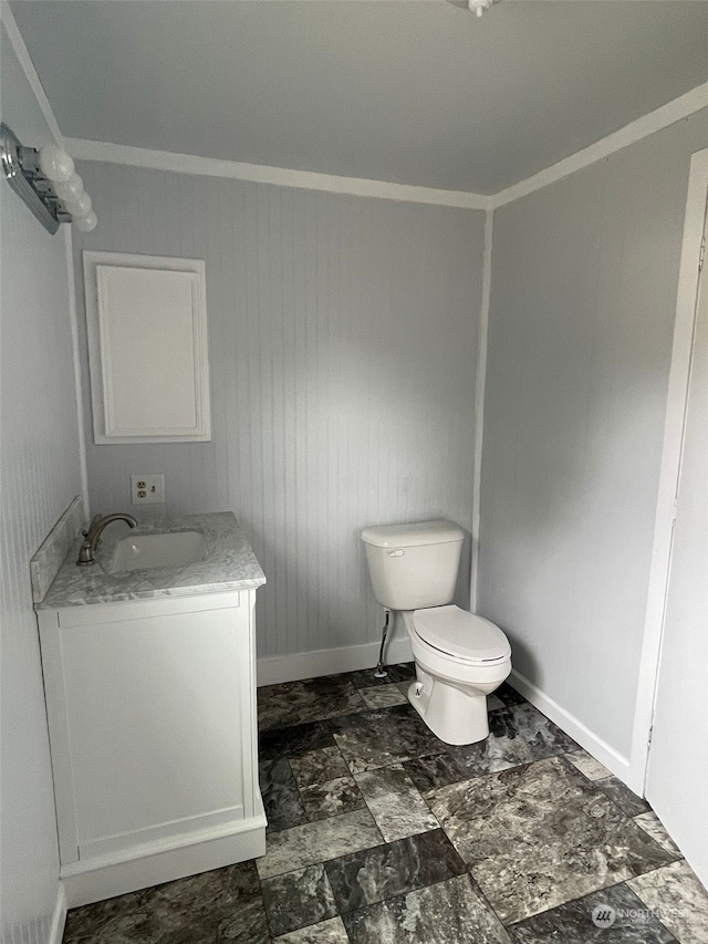 bathroom featuring vanity, wooden walls, toilet, and ornamental molding