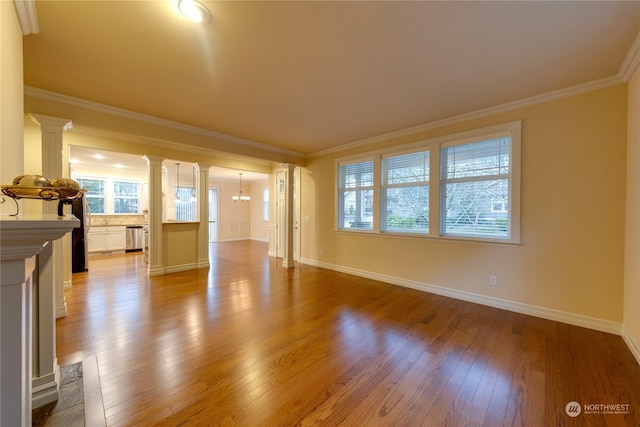 unfurnished living room featuring light wood-type flooring, decorative columns, an inviting chandelier, and crown molding