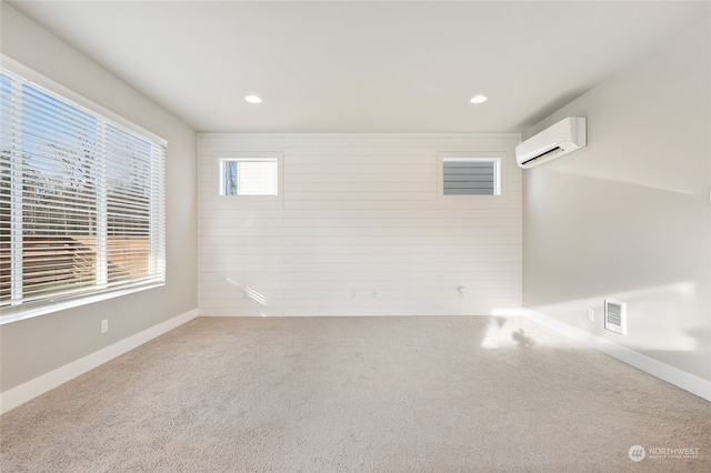 carpeted empty room featuring wooden walls and a wall unit AC