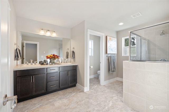 bathroom featuring vanity, a tile shower, and toilet