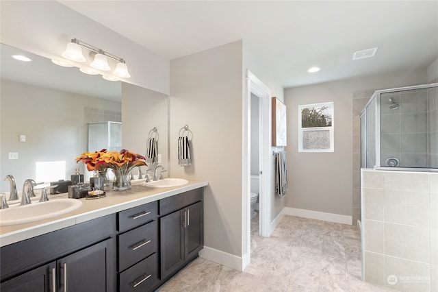 bathroom featuring vanity, a shower with shower door, and toilet