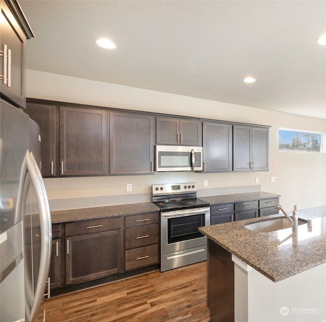 kitchen featuring appliances with stainless steel finishes, sink, dark stone countertops, and dark brown cabinets