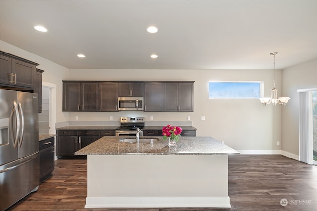 kitchen with sink, light stone counters, dark brown cabinets, a center island with sink, and stainless steel appliances