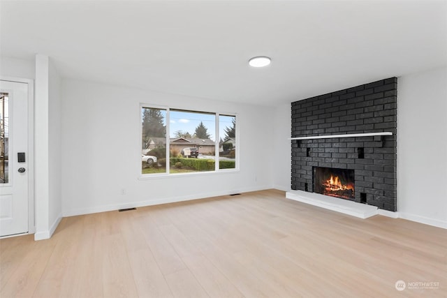 unfurnished living room featuring light hardwood / wood-style floors and a brick fireplace