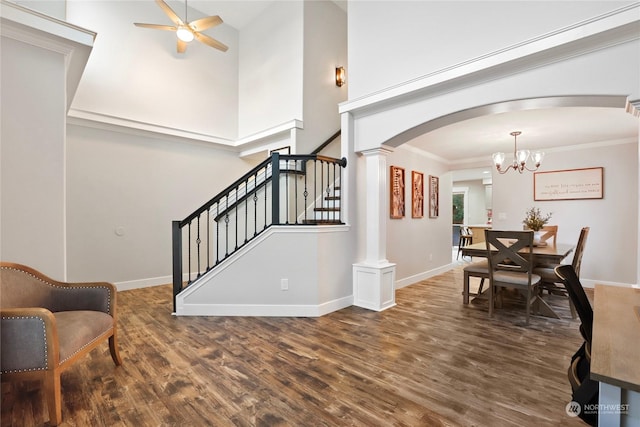 interior space featuring ceiling fan with notable chandelier, ornamental molding, dark wood-type flooring, and decorative columns