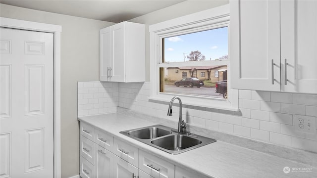 kitchen featuring backsplash, sink, and white cabinets