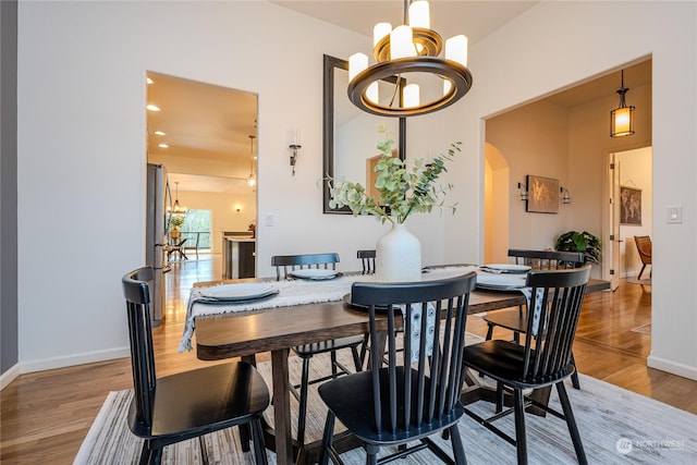 dining area with hardwood / wood-style floors and a notable chandelier