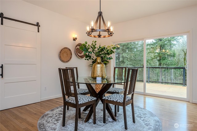 dining area with a notable chandelier, light hardwood / wood-style flooring, and a barn door