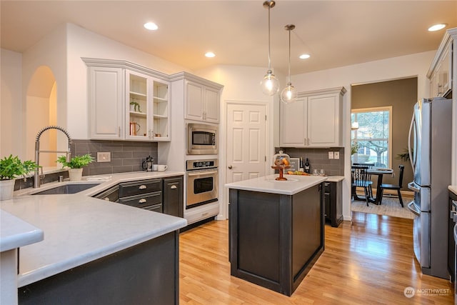 kitchen with stainless steel appliances, a center island, white cabinetry, and sink