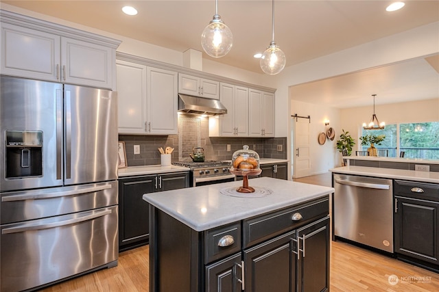 kitchen with stainless steel appliances, an inviting chandelier, hanging light fixtures, and a center island