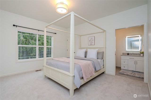 carpeted bedroom featuring sink and ensuite bath