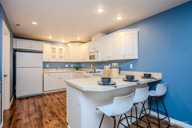 kitchen with sink, white appliances, white cabinetry, and kitchen peninsula