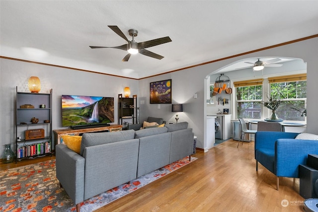 living room with ceiling fan, crown molding, washer and dryer, and wood-type flooring