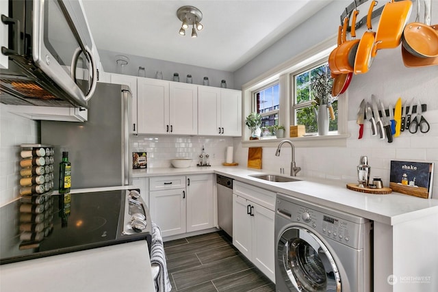 kitchen with backsplash, stainless steel appliances, sink, white cabinets, and washer / clothes dryer