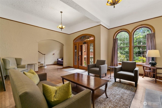 living room with a wealth of natural light, a notable chandelier, a textured ceiling, and light wood-type flooring