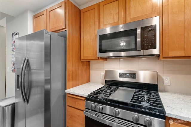 kitchen featuring decorative backsplash, light stone countertops, and appliances with stainless steel finishes