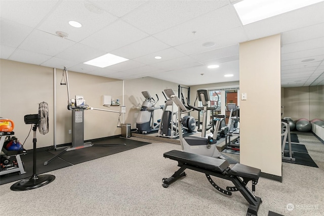 workout area with a paneled ceiling and dark colored carpet