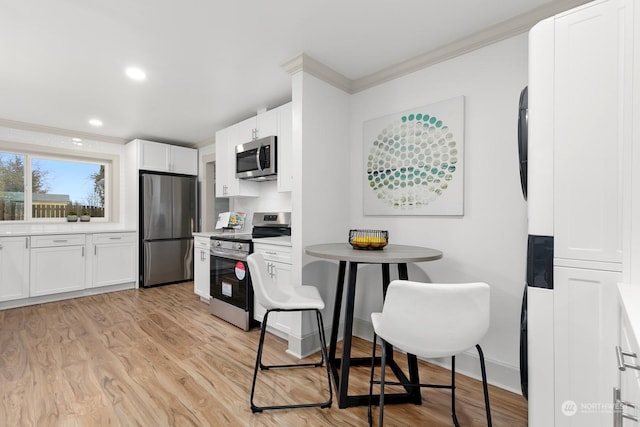 kitchen with appliances with stainless steel finishes, backsplash, crown molding, light hardwood / wood-style flooring, and white cabinets