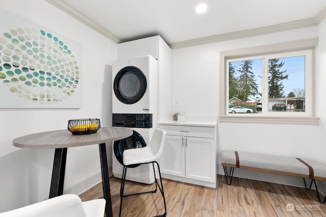 dining area with light hardwood / wood-style floors, crown molding, and stacked washer / drying machine