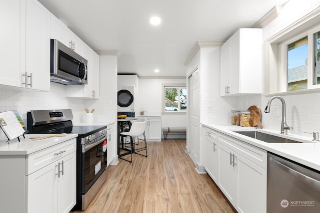 kitchen with white cabinets, stacked washer / dryer, and appliances with stainless steel finishes