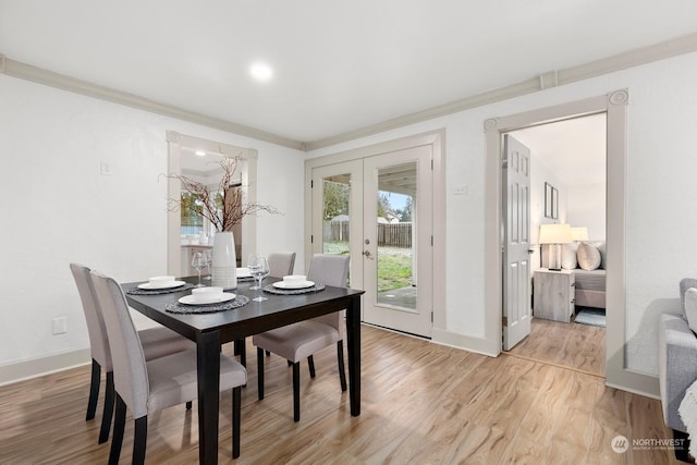 dining space featuring french doors, light wood-type flooring, and crown molding