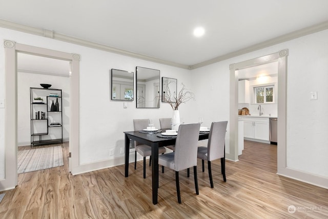 dining room with light wood-type flooring and crown molding