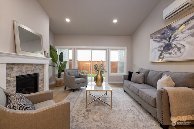 living room featuring a stone fireplace, light hardwood / wood-style floors, and a wall mounted air conditioner