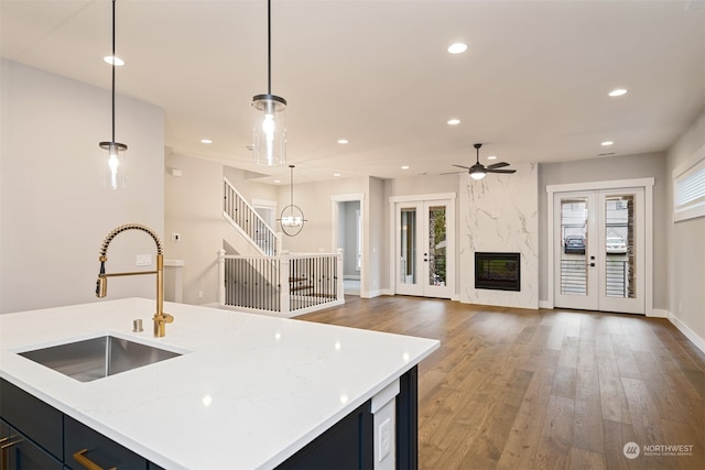 kitchen with a fireplace, decorative light fixtures, light stone counters, and sink