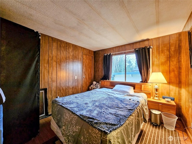 bedroom featuring wood walls and a textured ceiling