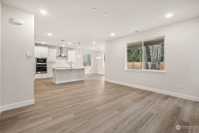 unfurnished living room featuring sink and light hardwood / wood-style flooring