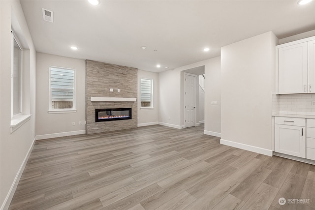 unfurnished living room featuring light hardwood / wood-style flooring and a tiled fireplace