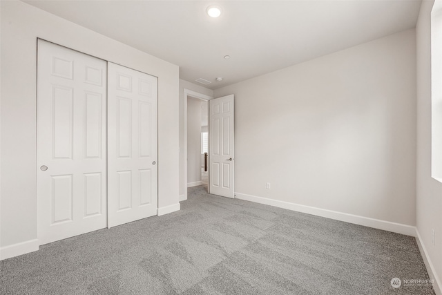 unfurnished bedroom with light carpet and a closet