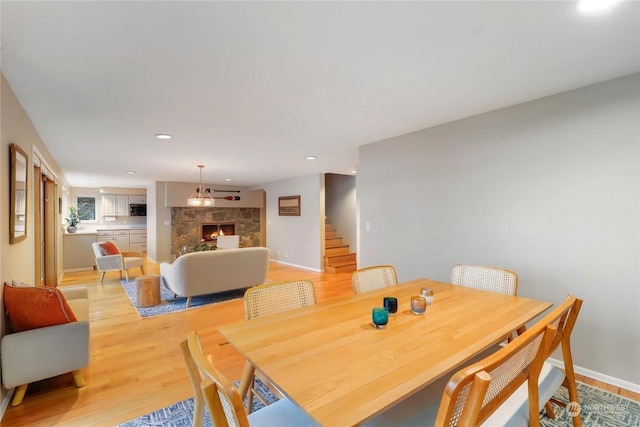 dining area featuring light hardwood / wood-style floors and a stone fireplace