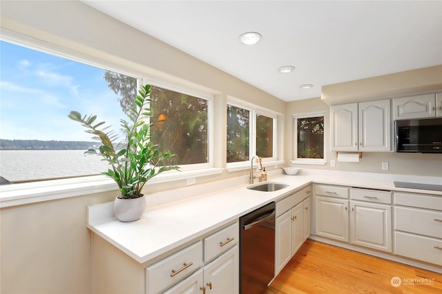 kitchen with sink, white cabinets, a water view, light wood-type flooring, and stainless steel appliances