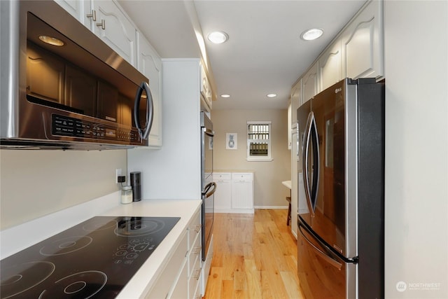 kitchen with white cabinets, light wood-type flooring, and appliances with stainless steel finishes