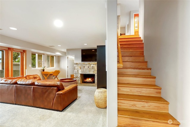 staircase featuring carpet floors and a stone fireplace