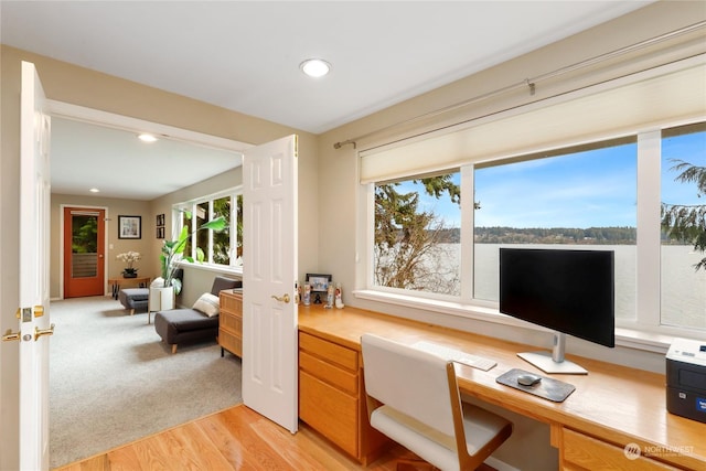 office featuring built in desk, a healthy amount of sunlight, and light hardwood / wood-style floors