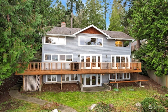 back of house featuring a lawn, a deck, and french doors