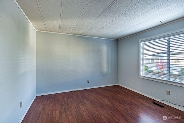 unfurnished room with a textured ceiling, crown molding, and dark wood-type flooring