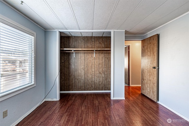 unfurnished bedroom with multiple windows, dark hardwood / wood-style floors, and a closet